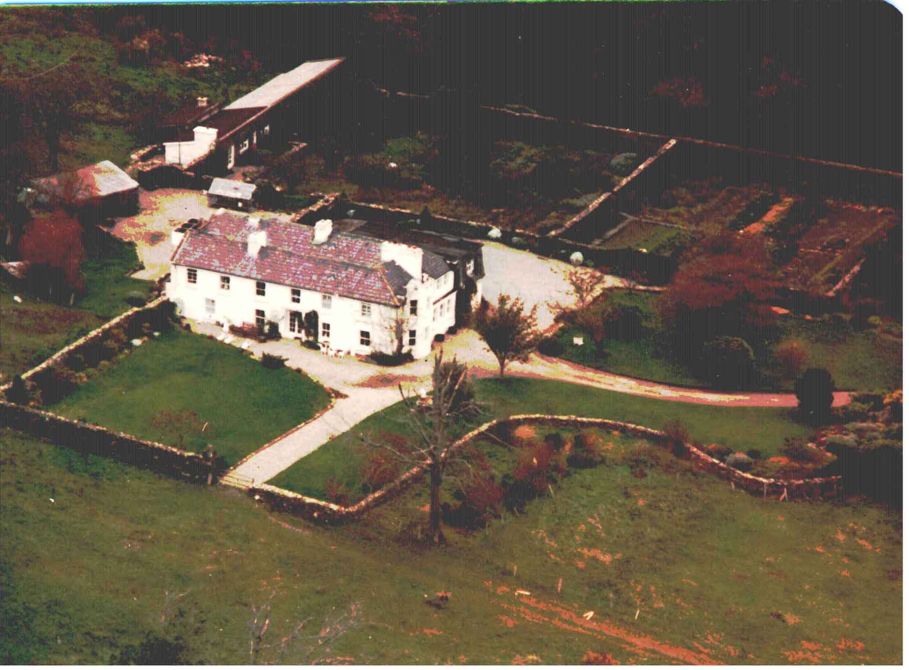 Aerial view of the House with the walled Vegetable Garden and Orchard behind:the Stables 
are to the left